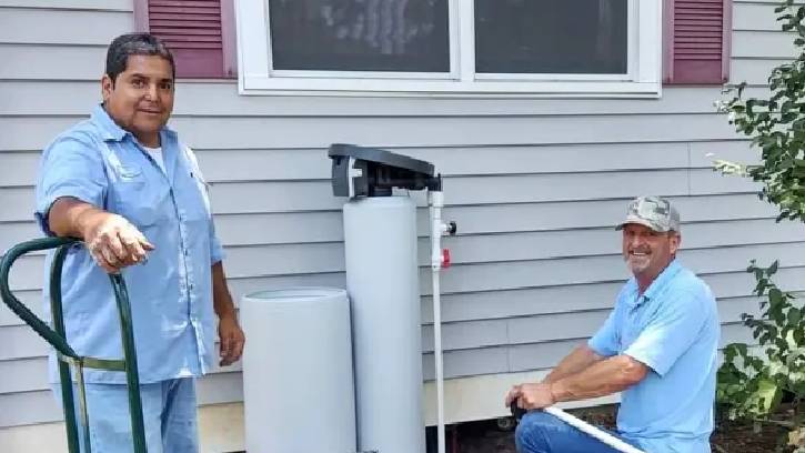 Water of Texas technicians beside a residential water-treatment installation